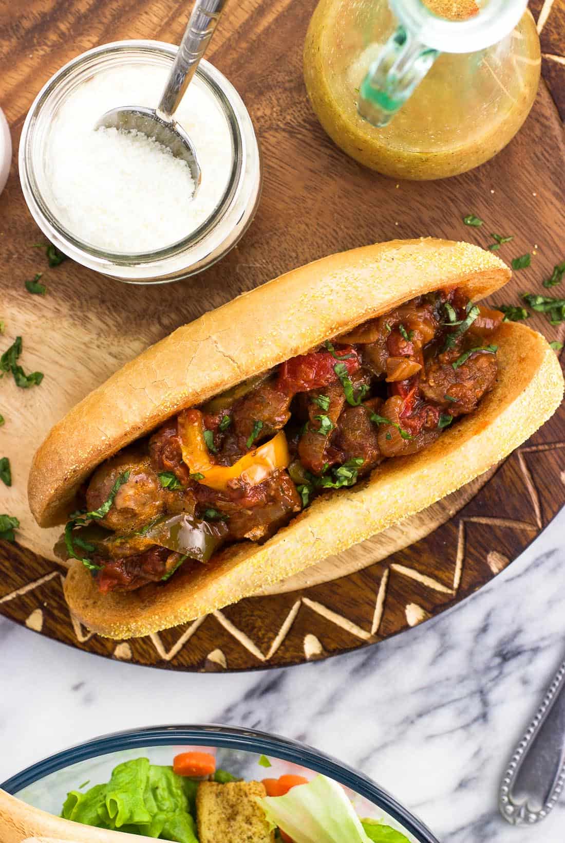 Italian sausage and peppers scooped onto a lightly toasted sandwich roll on a wooden serving board