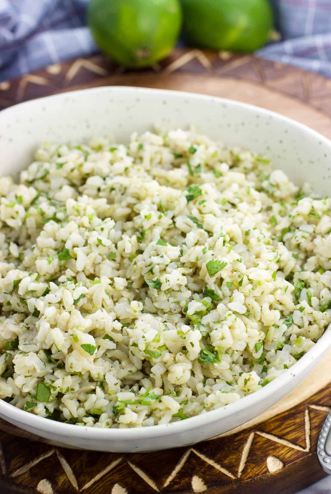 A bowl of seasoned brown rice with limes in the background.