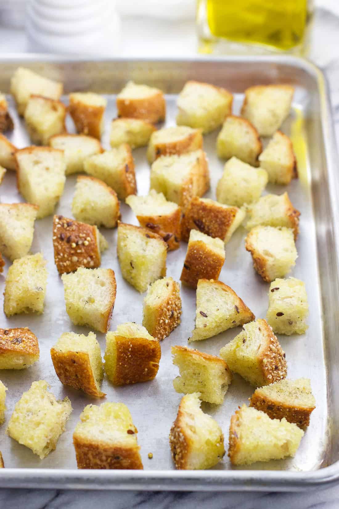 Croutons pre-bake on a steel rimmed baking sheet.