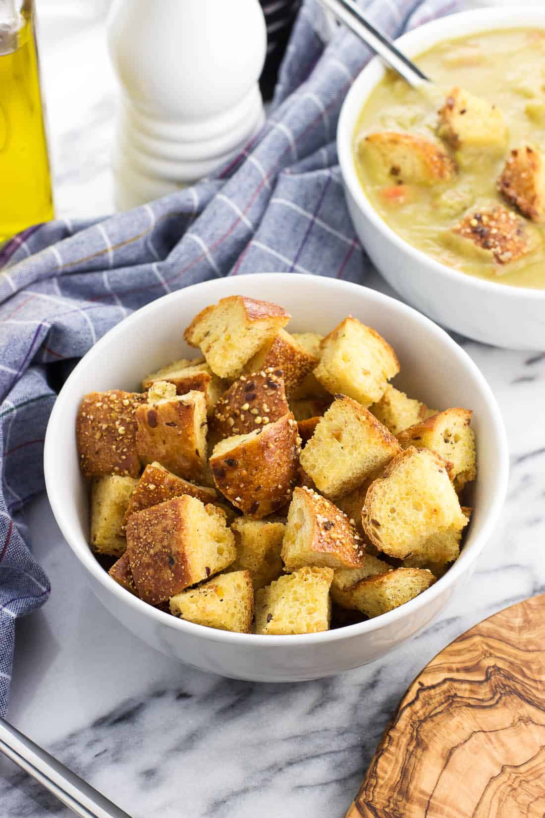 Homemade croutons in a bowl next to a bowl of soup.