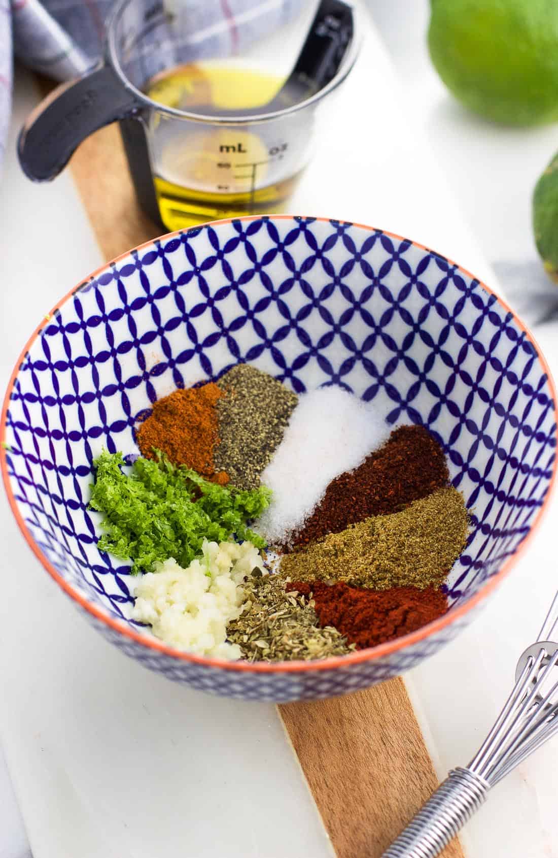 The dry spices, minced garlic, and lime zest used in the glaze in a small bowl