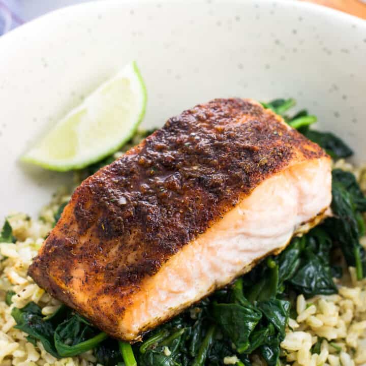 A cooked salmon fillet served on a bed of sauteed spinach over rice