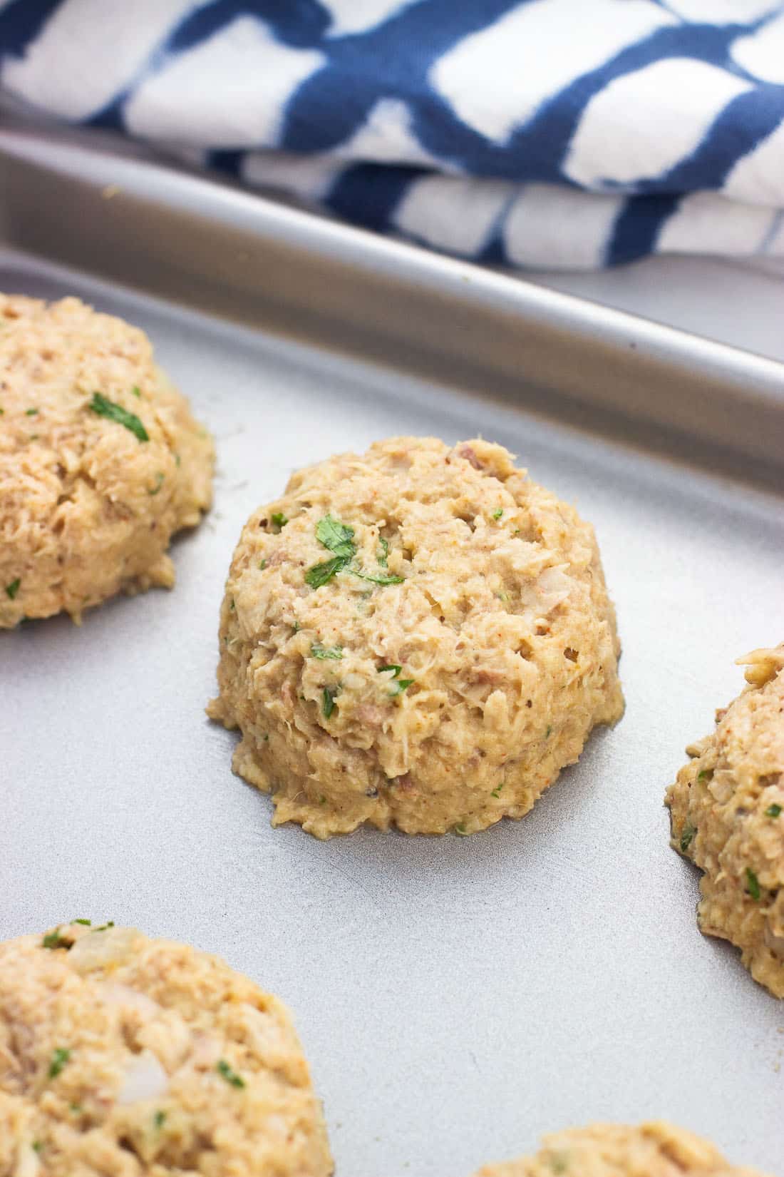 Shaped tuna cakes on a baking sheet before being baked.