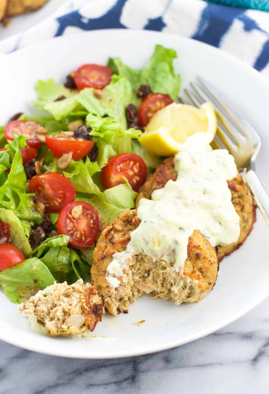 Healthy baked tuna cakes on a plate with a forkful removed from one of the cakes.