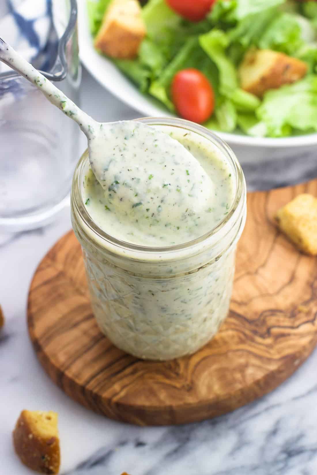 Homemade ranch dressing in a glass jar with a spoon