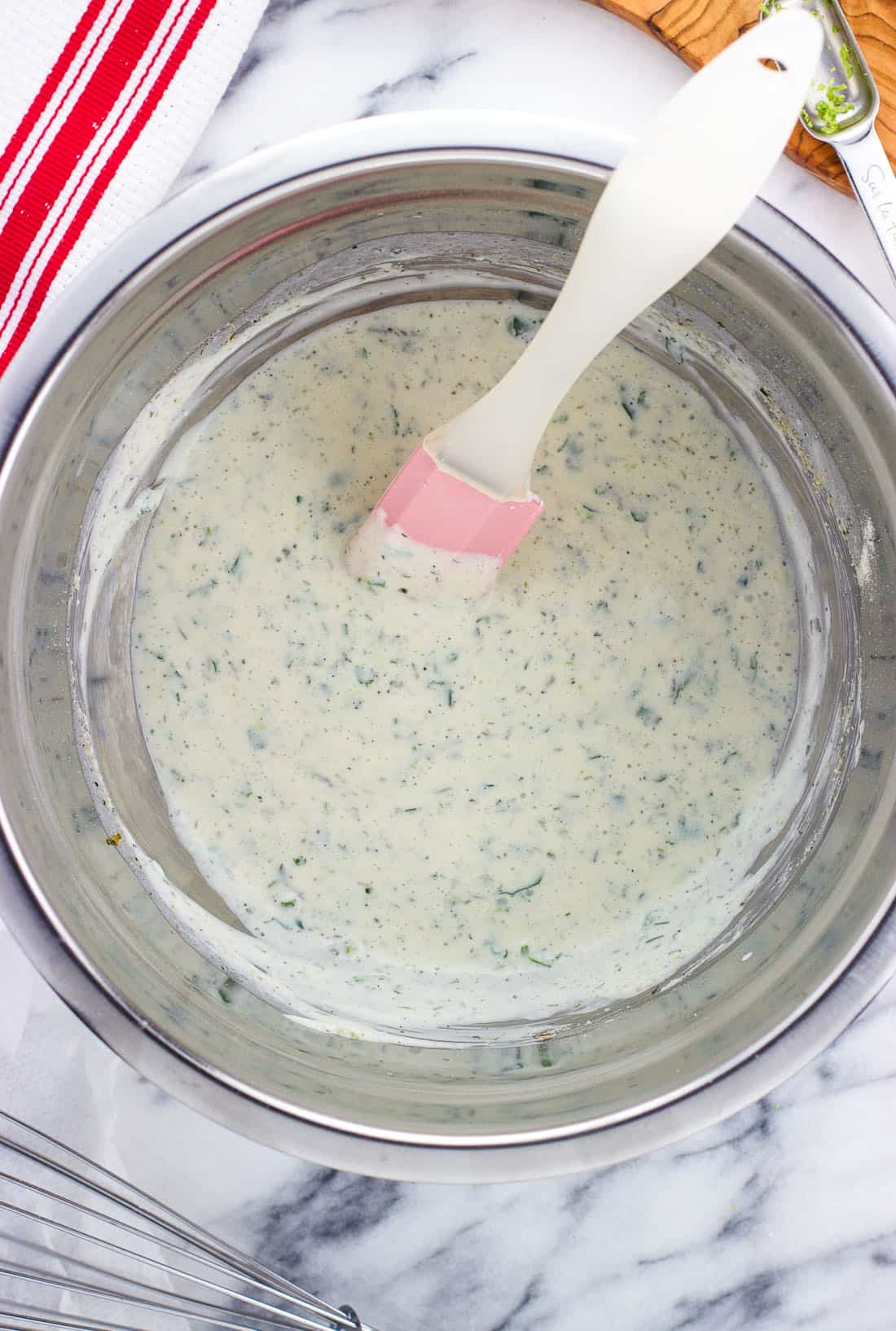 An overhead picture of cilantro lime ranch dressing mixed together in a bowl with a spatula