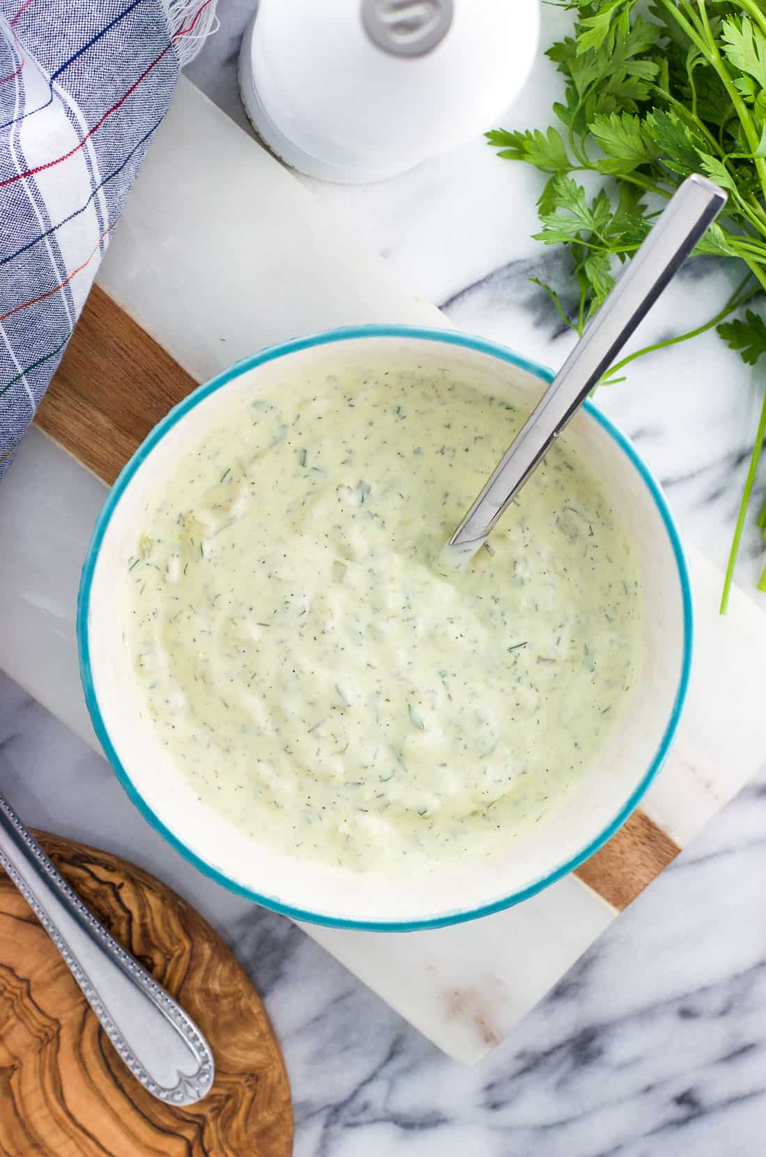 An overhead shot of prepared tartar sauce in a ceramic bowl with a spoon.