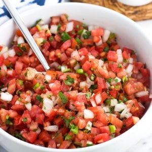 Pico de gallo in a serving bowl with a spoon