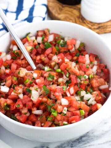 Pico de gallo in a serving bowl with a spoon