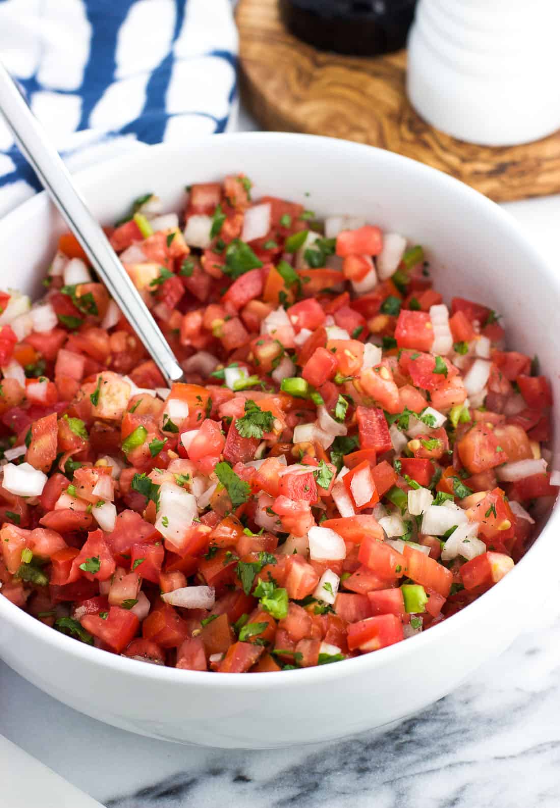 Pico de gallo in a serving bowl with a spoon