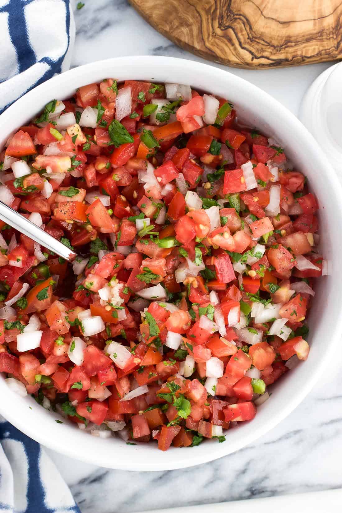 An overhead shot of pico de gallo in a serving bowl with a spoon