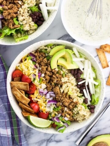 An overhead shot of quinoa turkey taco salad in a bowl with the toppings arranged in strips on top of the lettuce