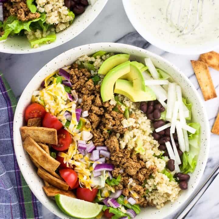 An overhead shot of quinoa turkey taco salad in a bowl with the toppings arranged in strips on top of the lettuce