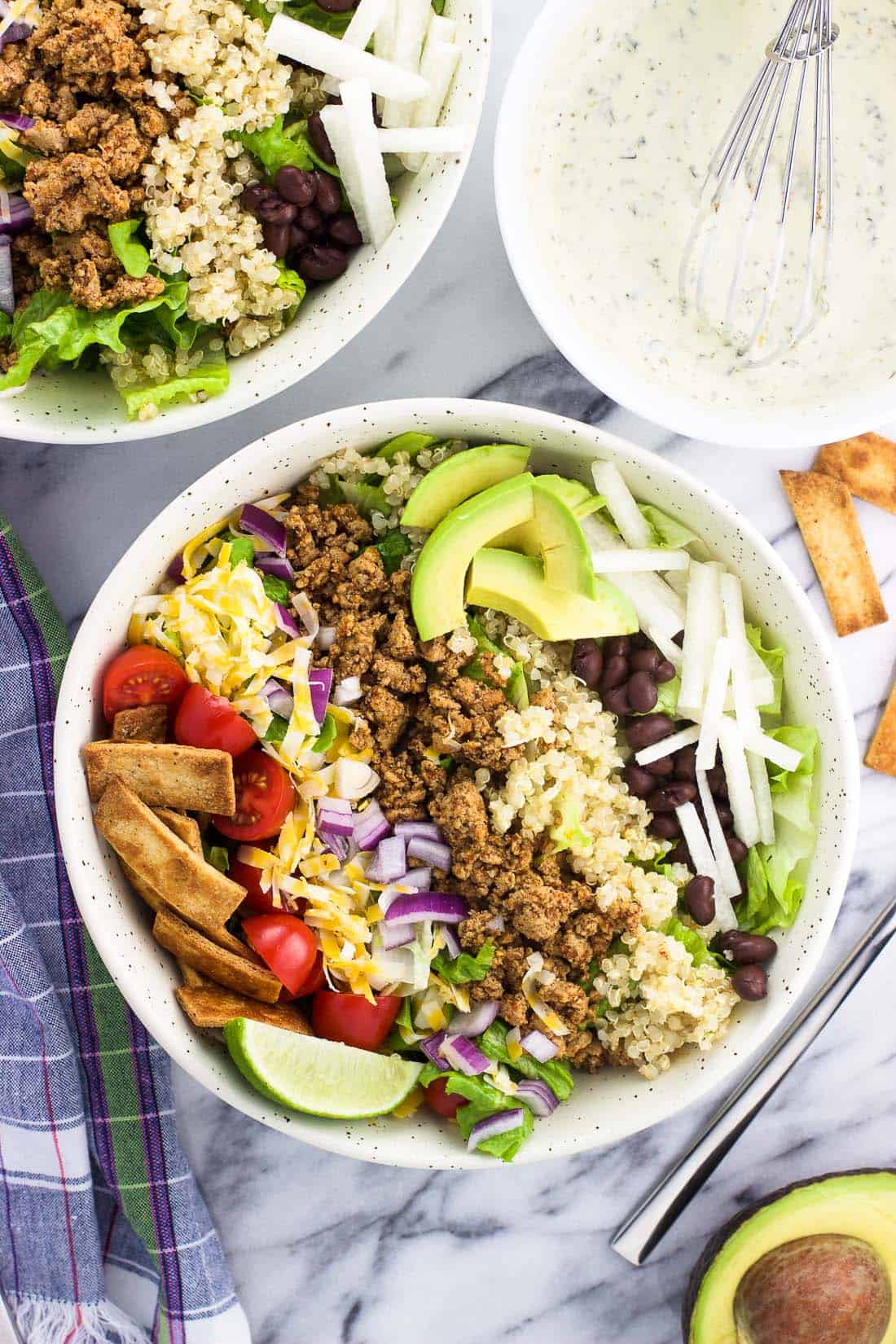 An overhead shot of quinoa turkey taco salad in a bowl with the toppings arranged in strips on top of the lettuce