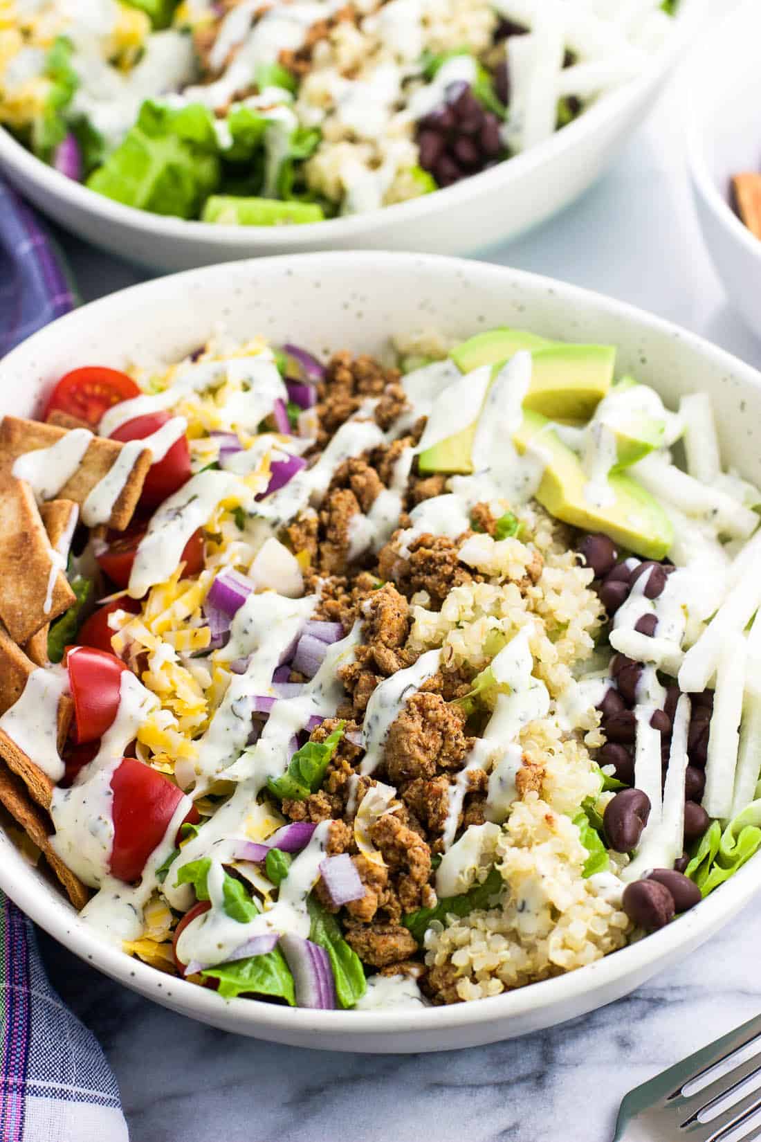 Taco salad in a bowl with a drizzle of cilantro lime ranch dressing over top