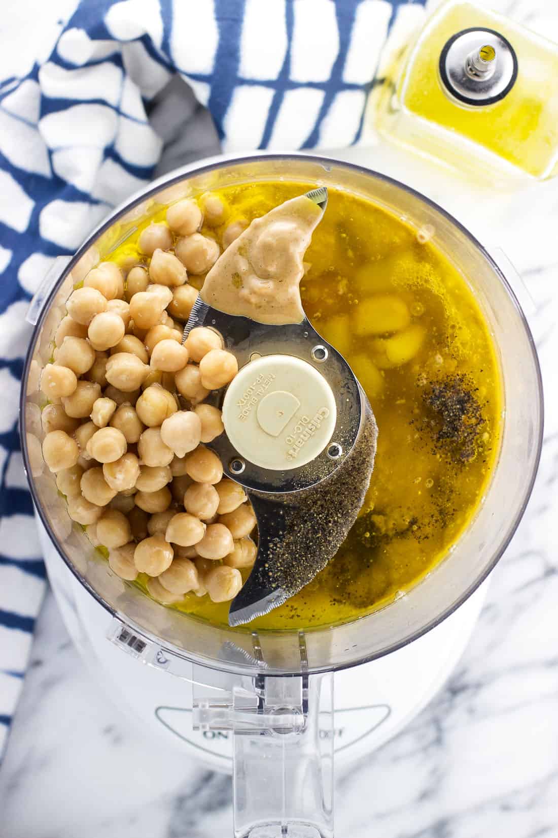 An overhead shot of all of the hummus ingredients in the bowl of a food processor