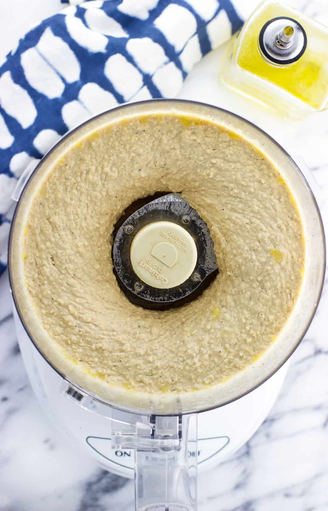 An overhead shot of the creamy hummus in the food processor after all of the ingredients have been combined
