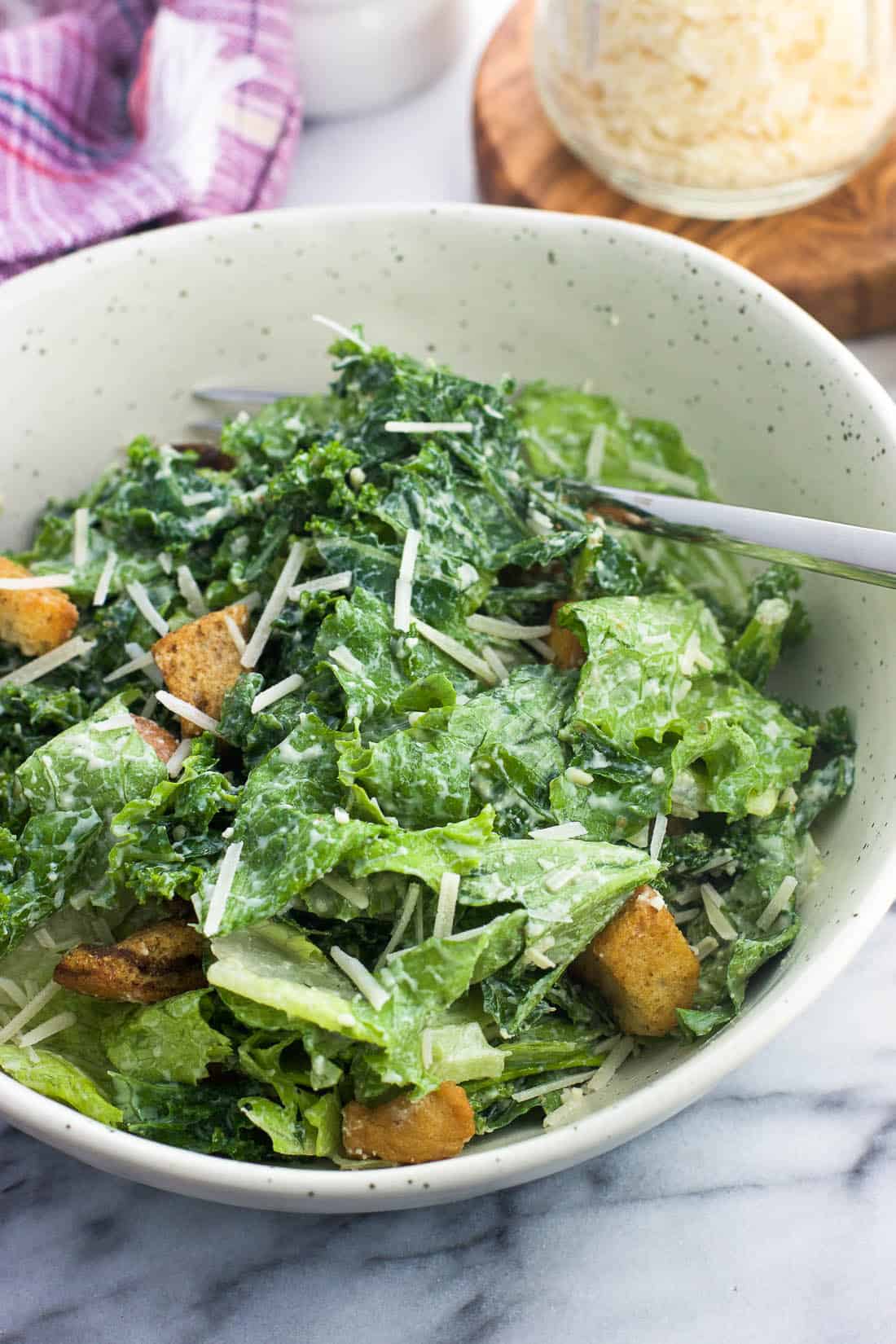 Caesar salad, made up of half kale and half lettuce, in a bowl with a fork