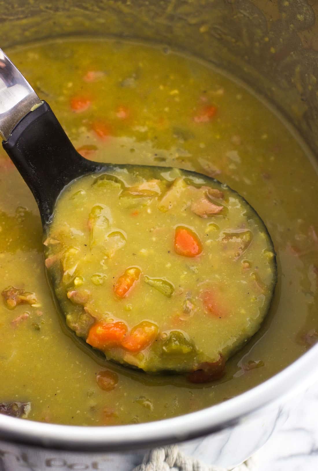 A ladle of split pea soup being raised from the Instant Pot.