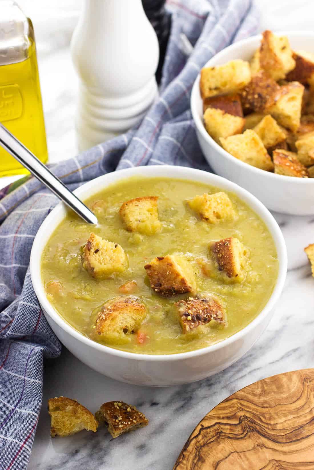 A bowl of split pea soup topped with croutons with a spoon.