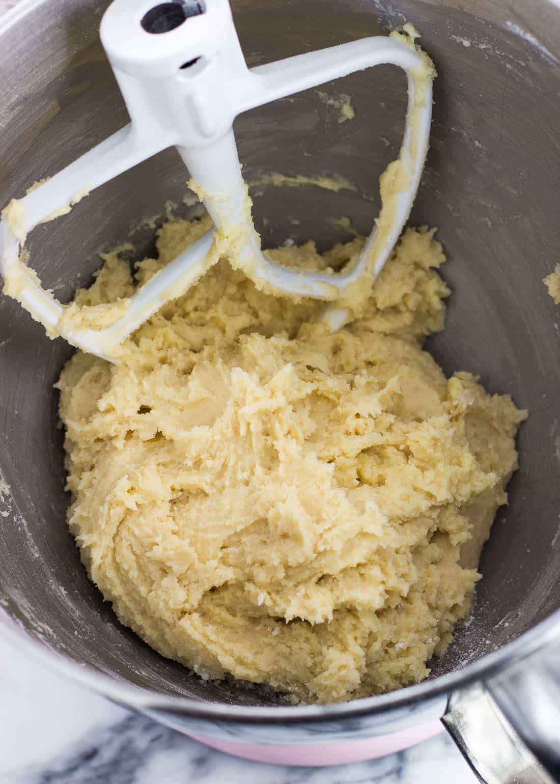 Italian ricotta cookie dough in a metal mixing bowl with the paddle attachment from a stand mixer