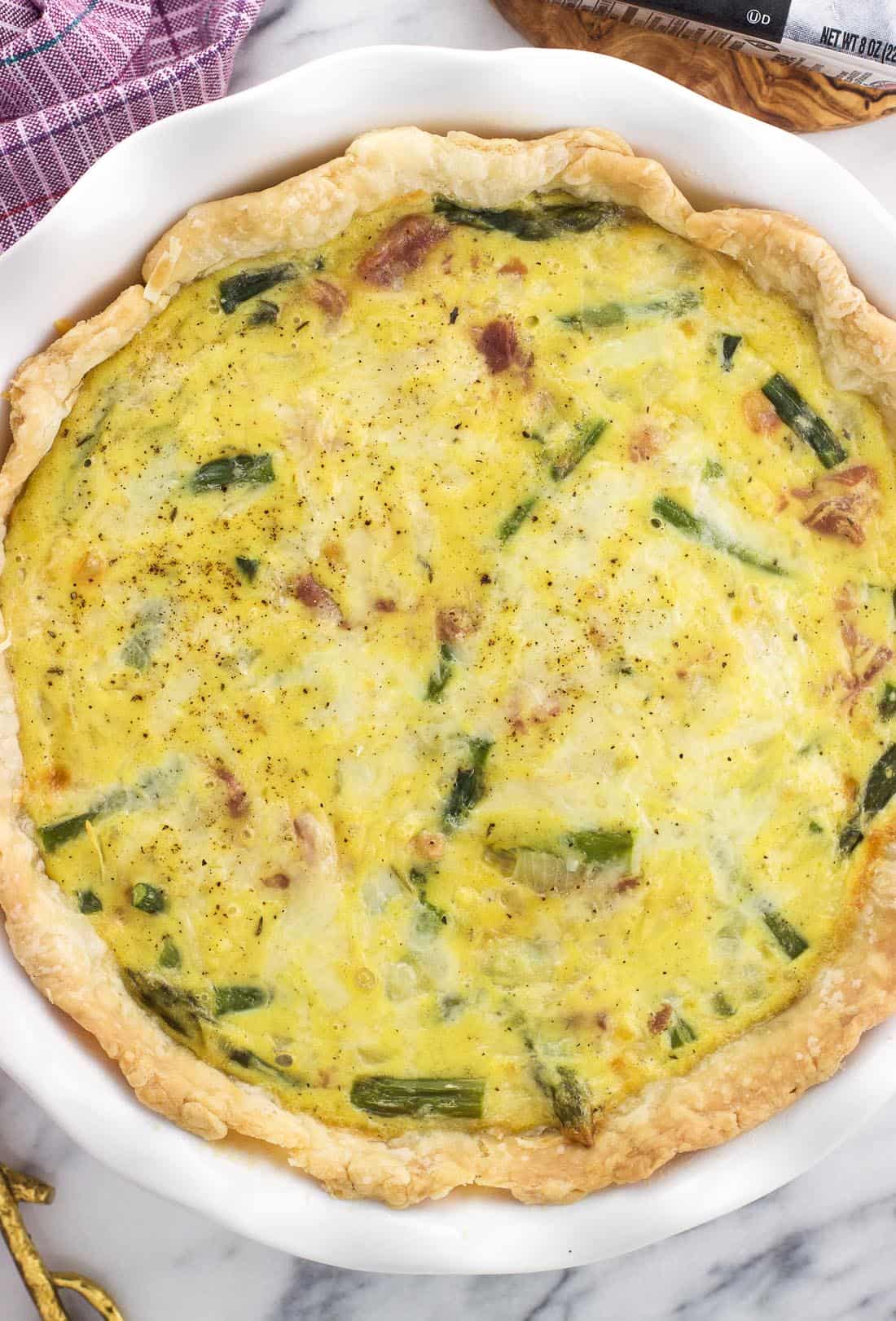 An overhead picture of the quiche in a pie plate before being sliced.