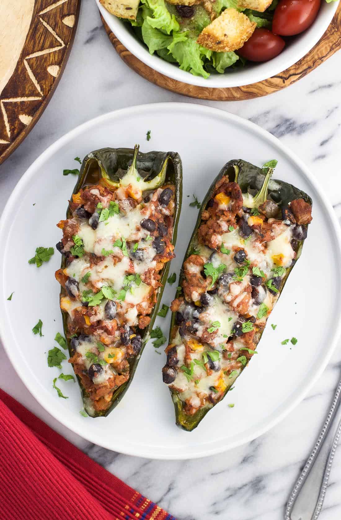 Two stuffed poblano pepper halves on a plate.