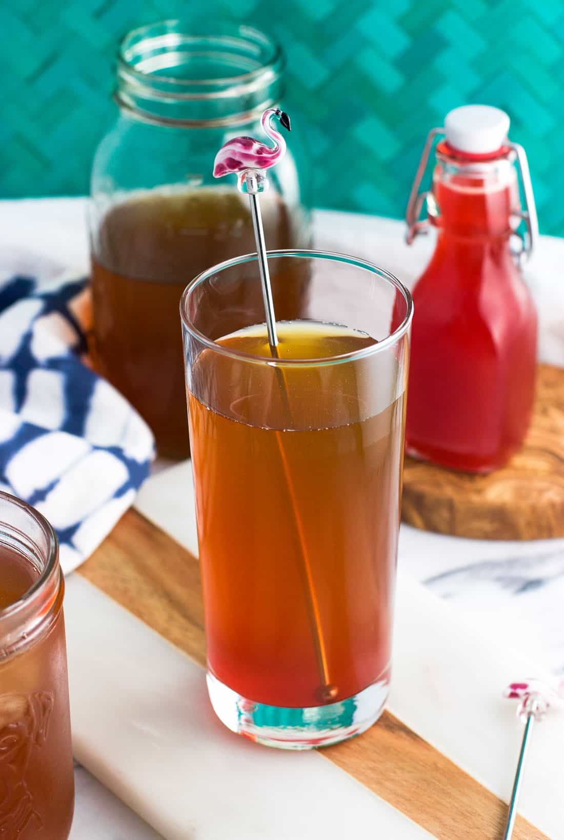 A tall glass of iced tea with a flamingo drink stirrer mixed with strawberry syrup