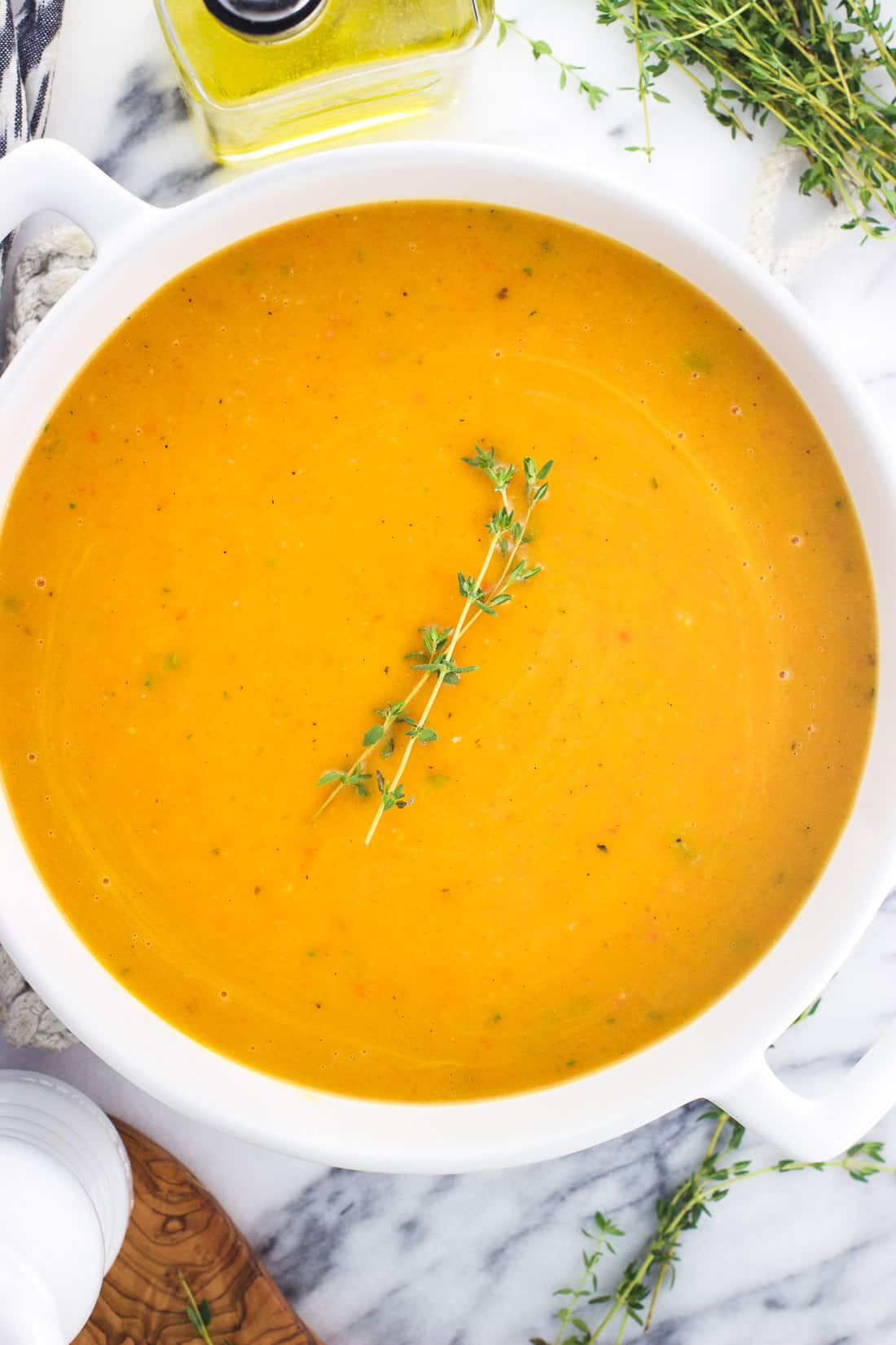 Butternut squash soup in a large soup pot topped with thyme sprigs.