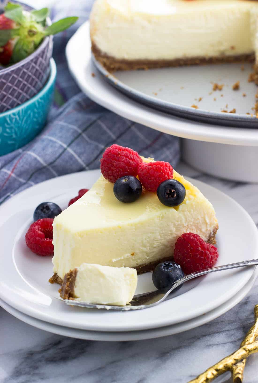 A slice of sour cream cheesecake on a dessert plate with a forkful taken out
