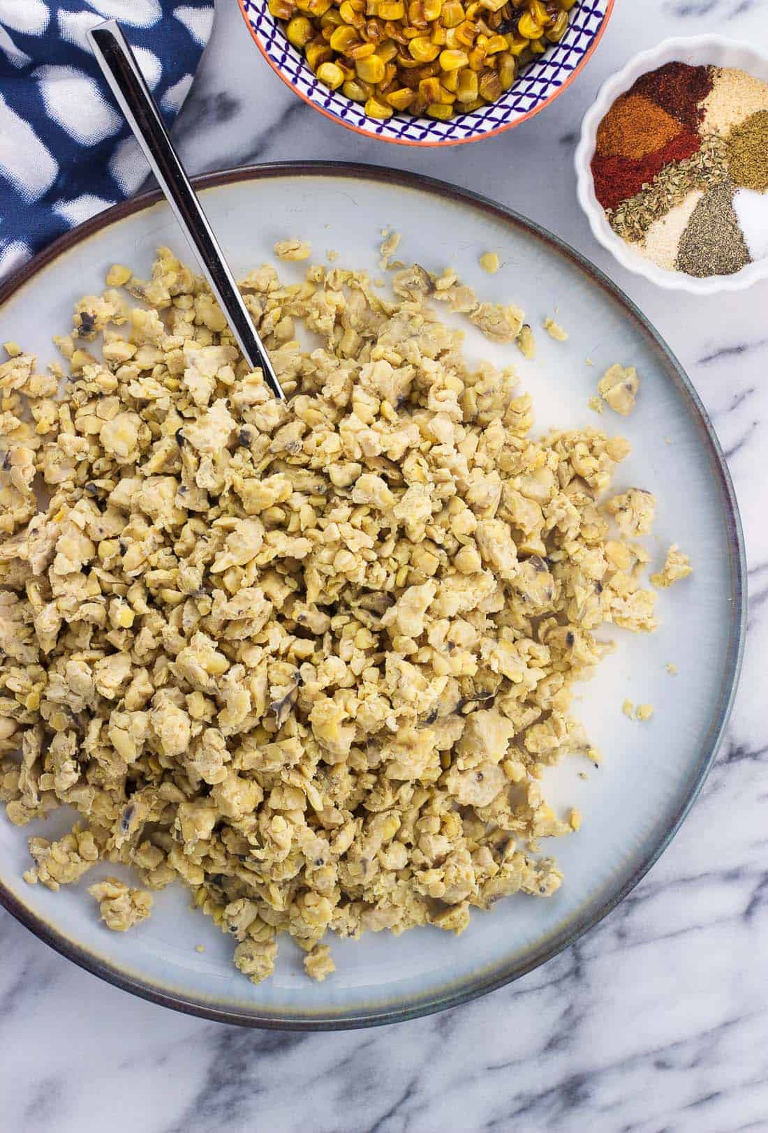 An overhead shot of crumbled tempeh on a plate with a spoon