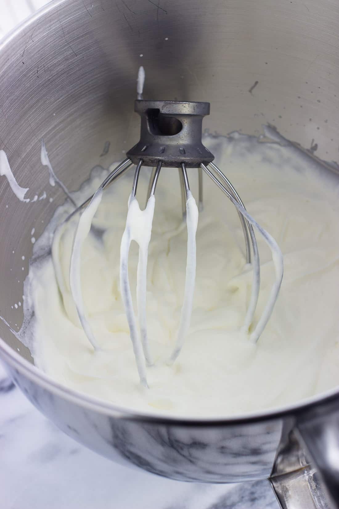 Cream whipped to soft peaks in a metal stand mixer bowl