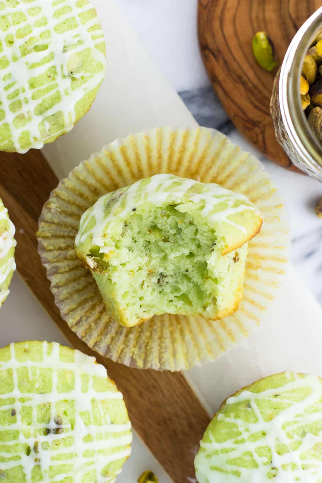 An overhead shot of a pistachio muffin with a bite taken out of it