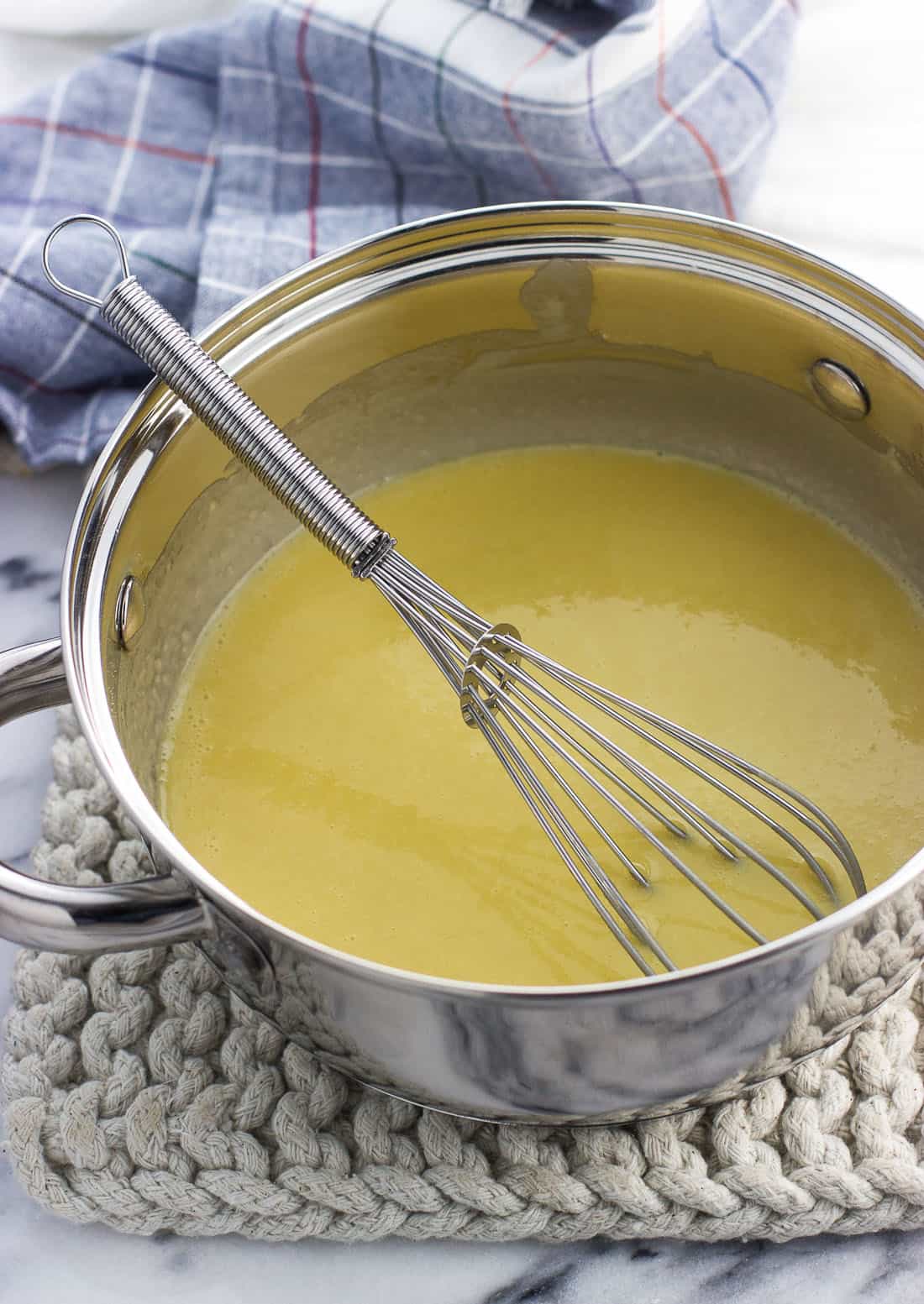 A small saucepan of the roux with a small metal whisk.