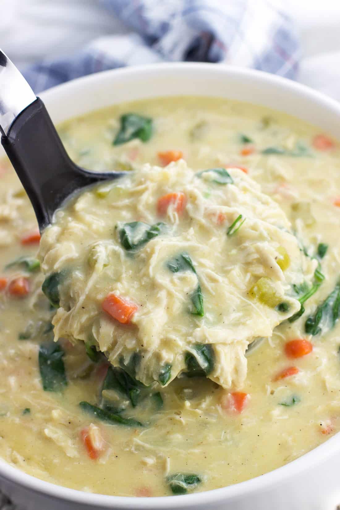 An overflowing ladle of soup being lifted out of the pot.