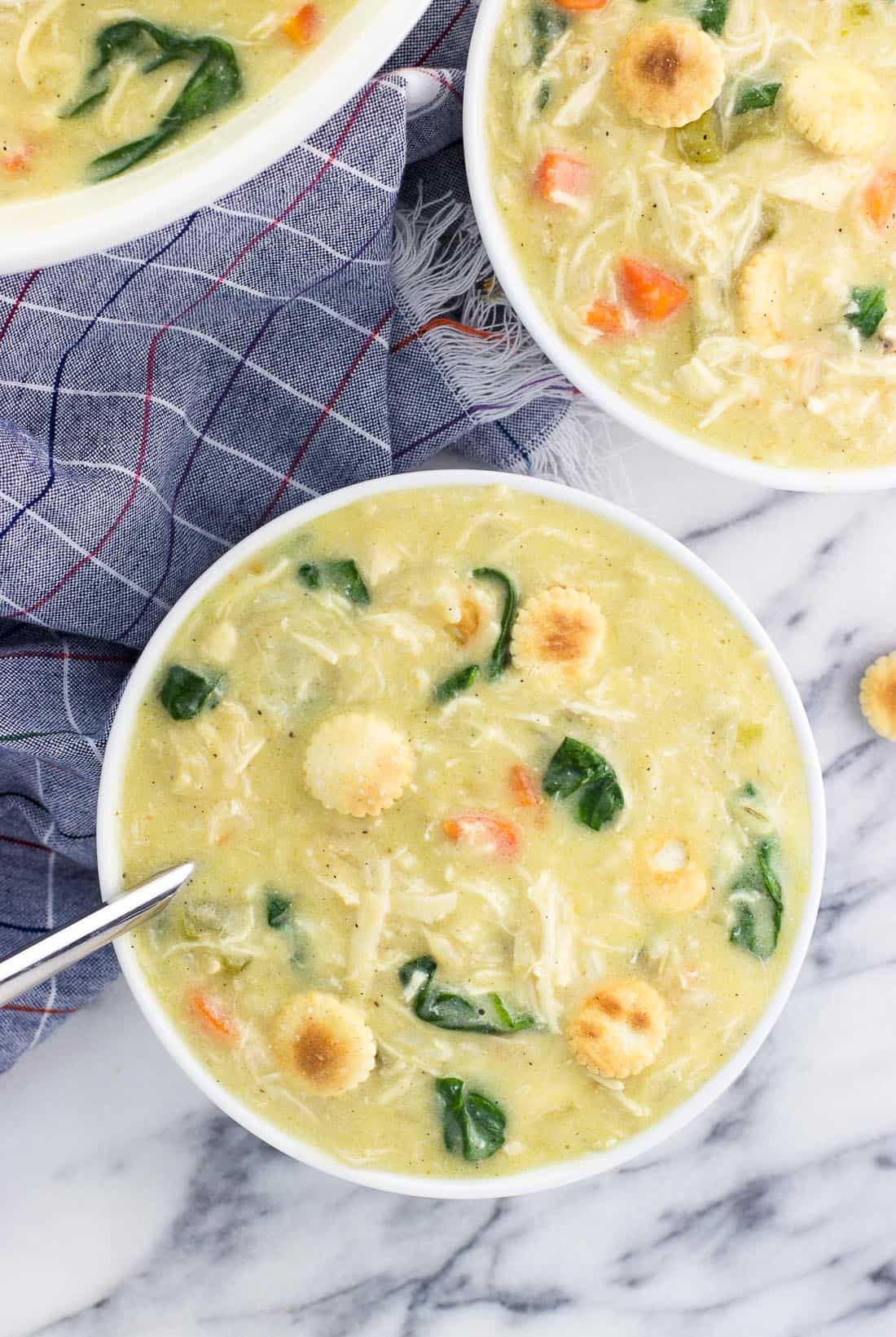 An overhead picture of two bowls of soup topped with oyster crackers next to the big soup pot.