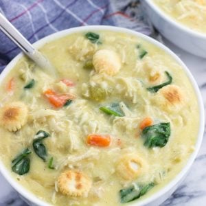 A big bowl of soup topped with oyster crackers with a big spoon