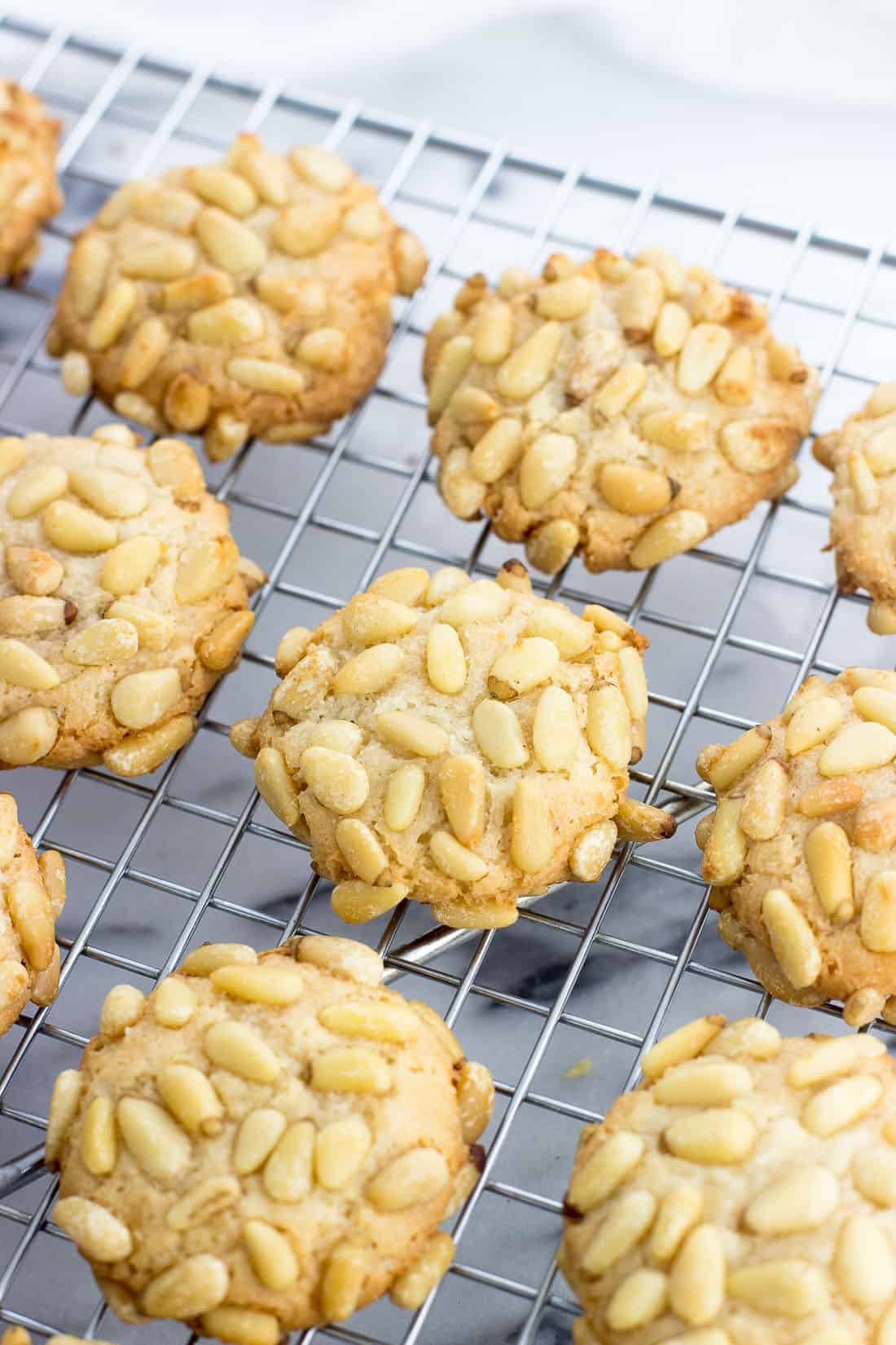 Pignoli cookies cooling on a wire rack.