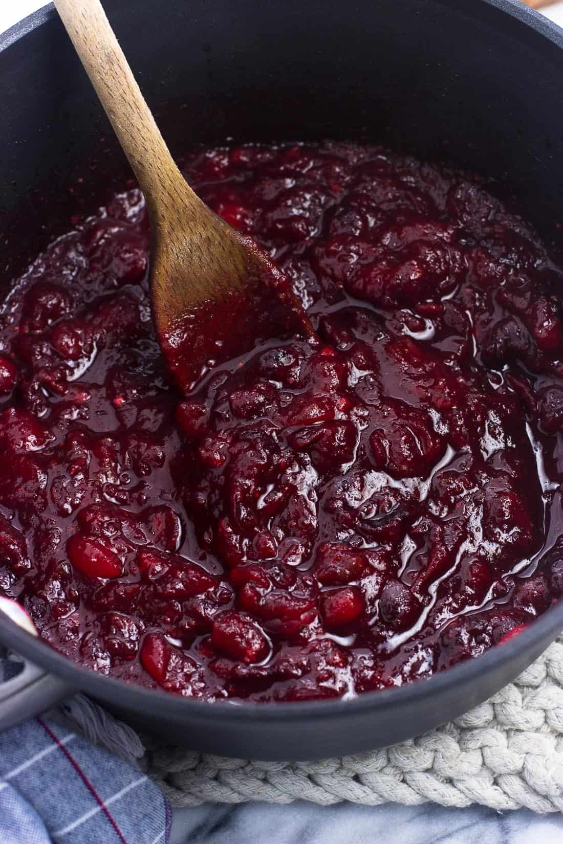 Cranberry sauce in a medium saucepan with a wooden spoon