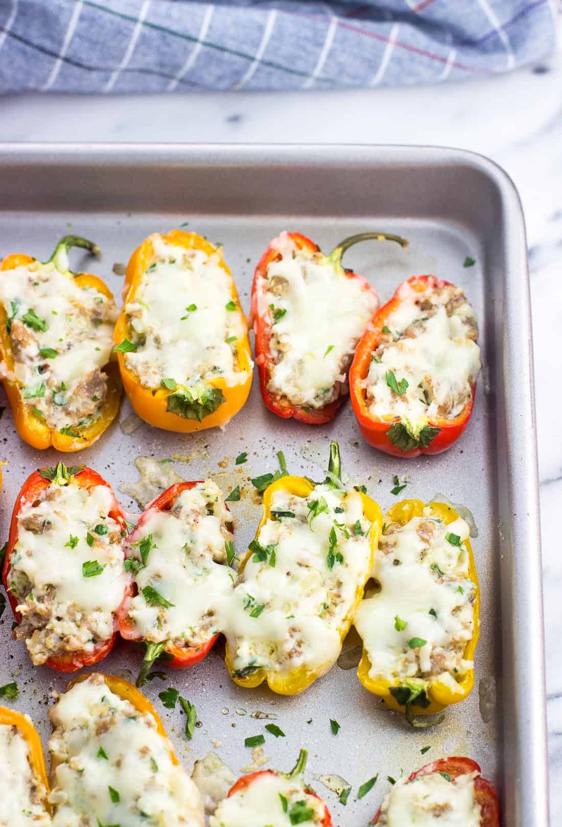 Stuffed mini peppers lined up next to one another on a baking sheet