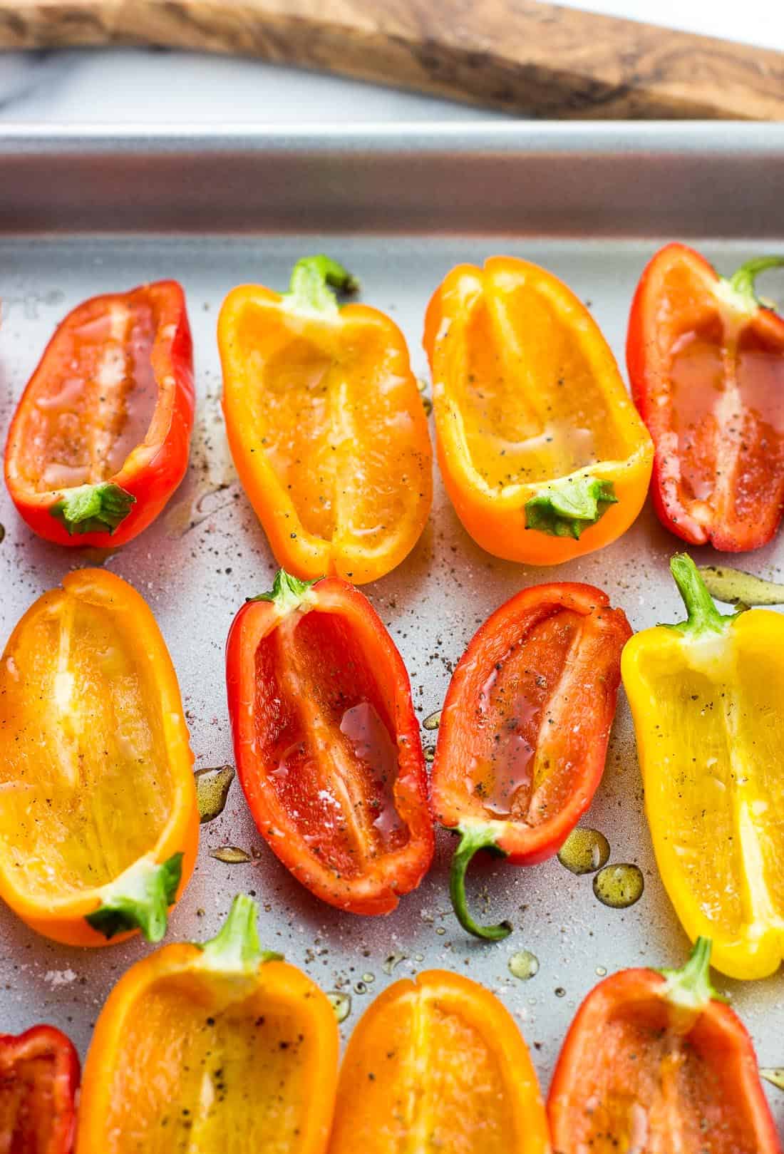 Roasted mini sweet pepper halves on a baking sheet prior to being stuffed.