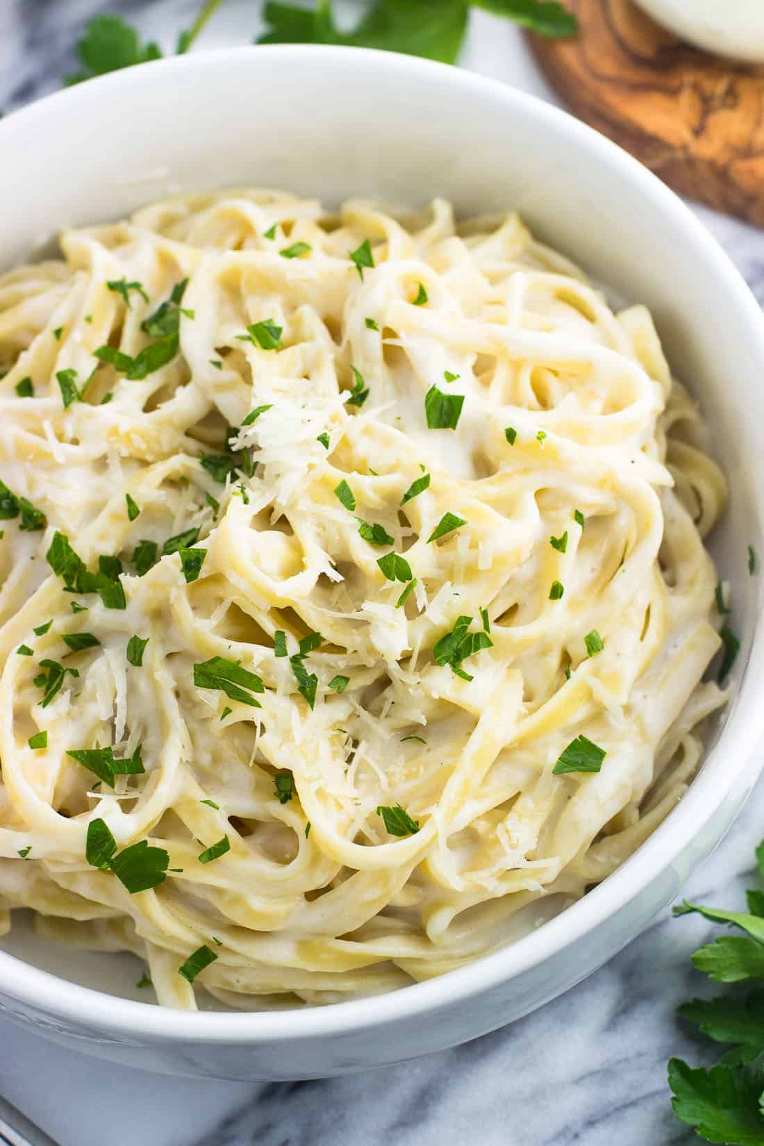 A close-up picture of healthy alfredo sauce on pasta in a serving bowl.