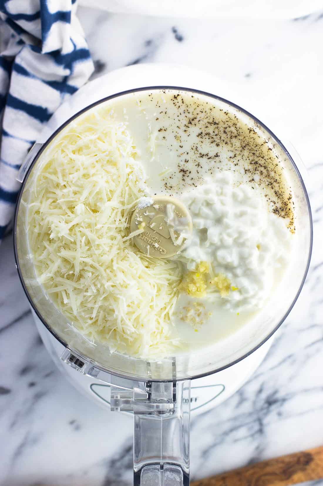 Healthy alfredo sauce ingredients in the bowl of a food processor before being blended