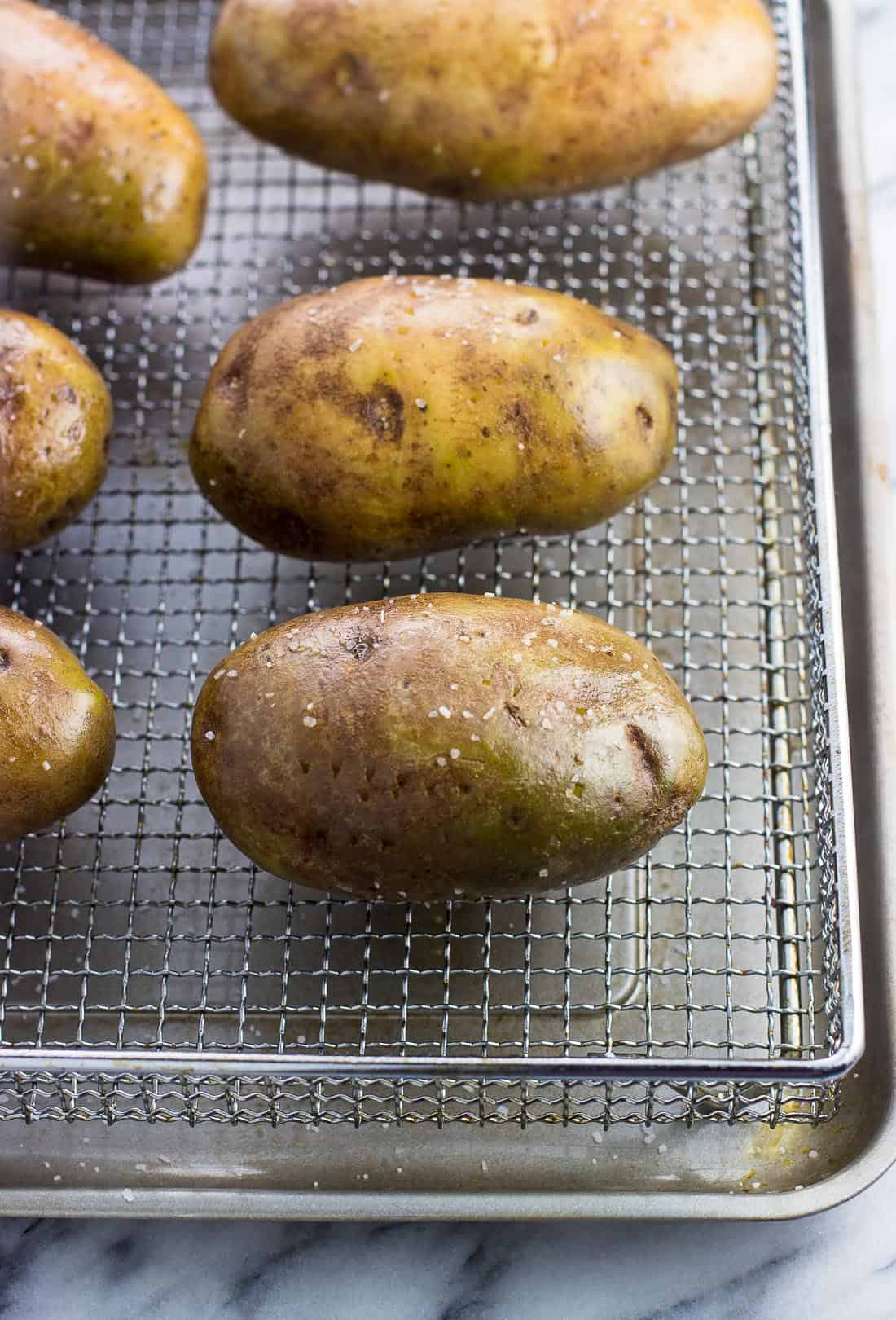 Oiled and salted potatoes on an air fryer basket.