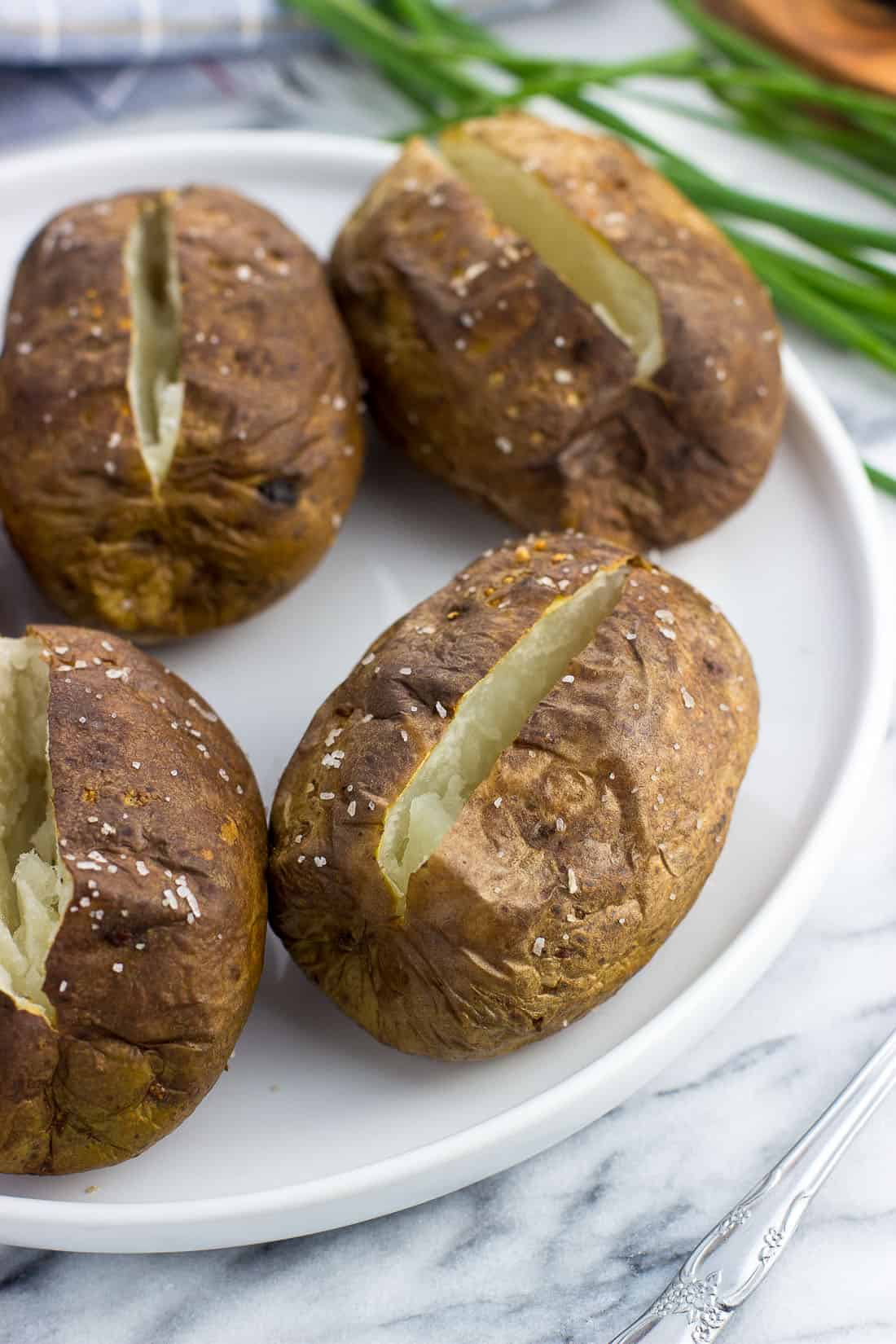 Air fried baked potatoes on a plate before adding toppings.