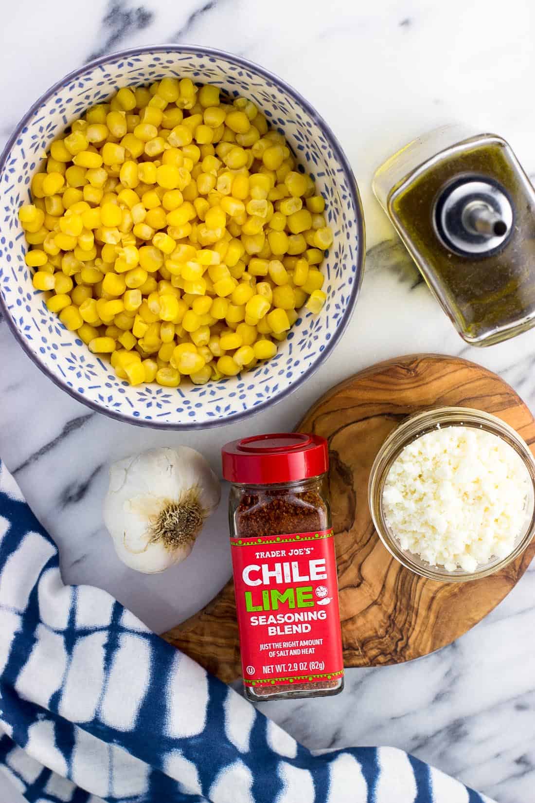 Ingredients for the skillet roasted corn on a marble board in separate containers