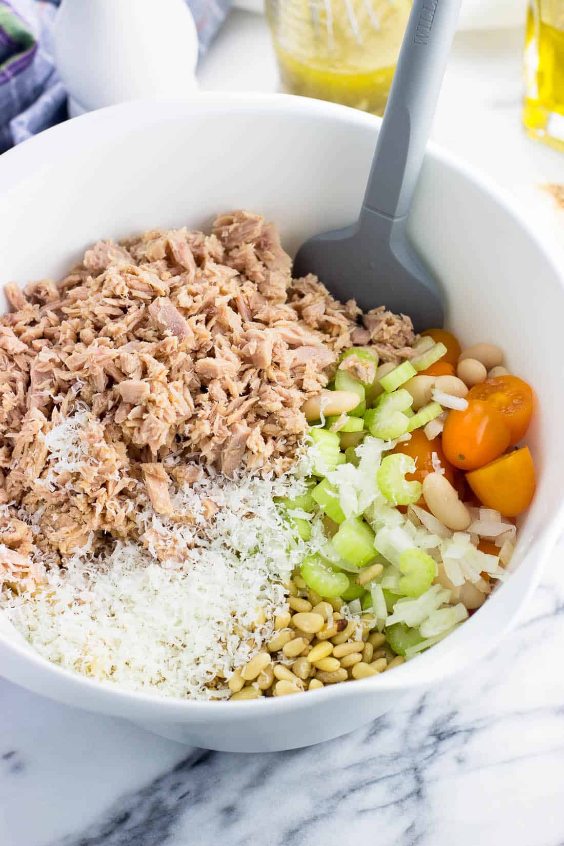 Cooked pasta and the rest of the pasta salad ingredients in a large bowl ready to mix.