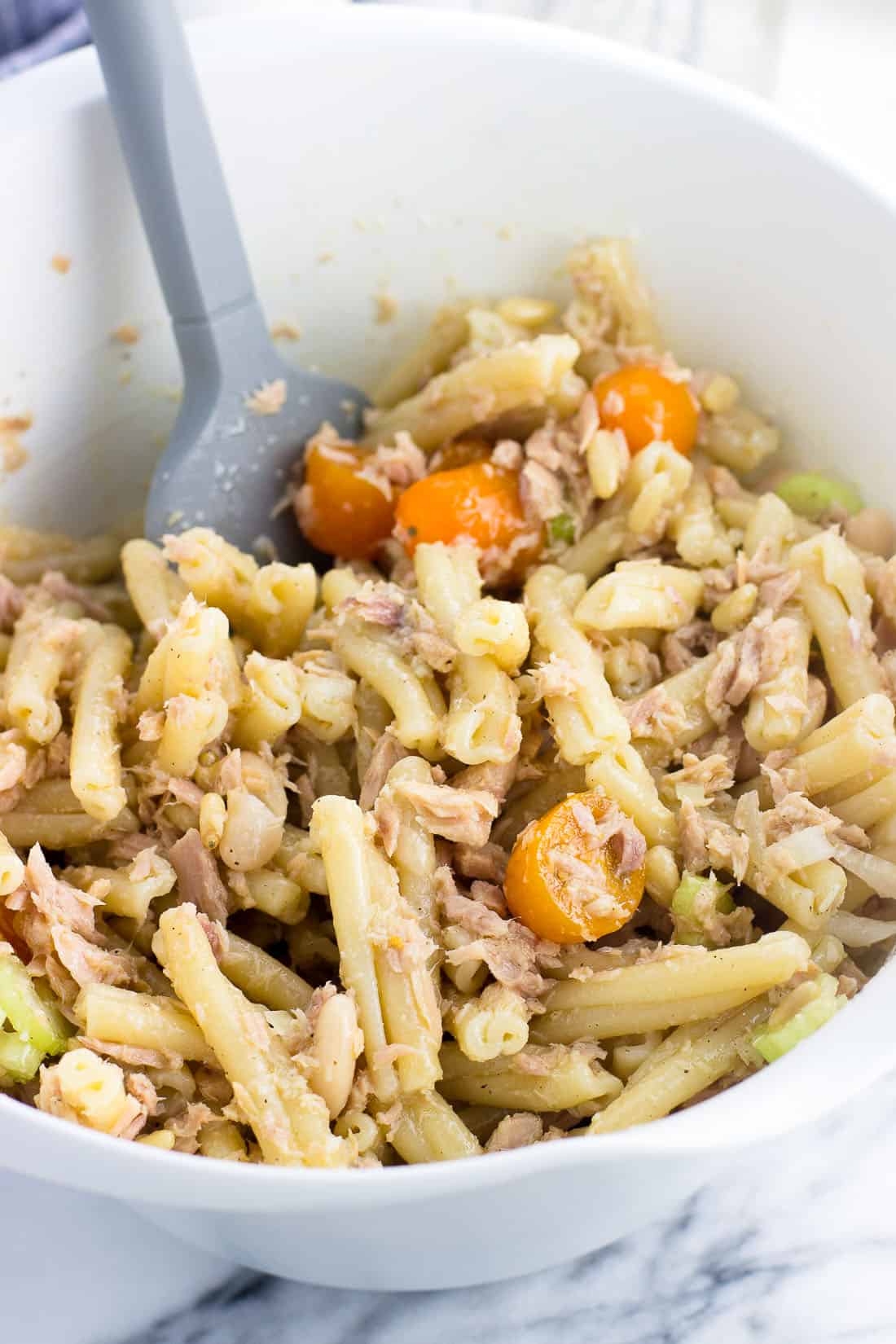 Tuna pasta salad mixed together in a bowl before adding the arugula.