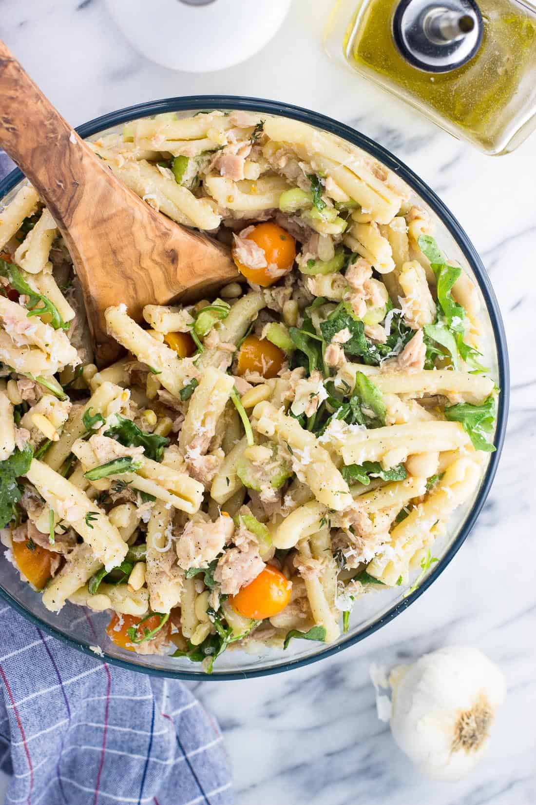 An overhead picture of pasta salad in a serving bowl with a wooden spoon.