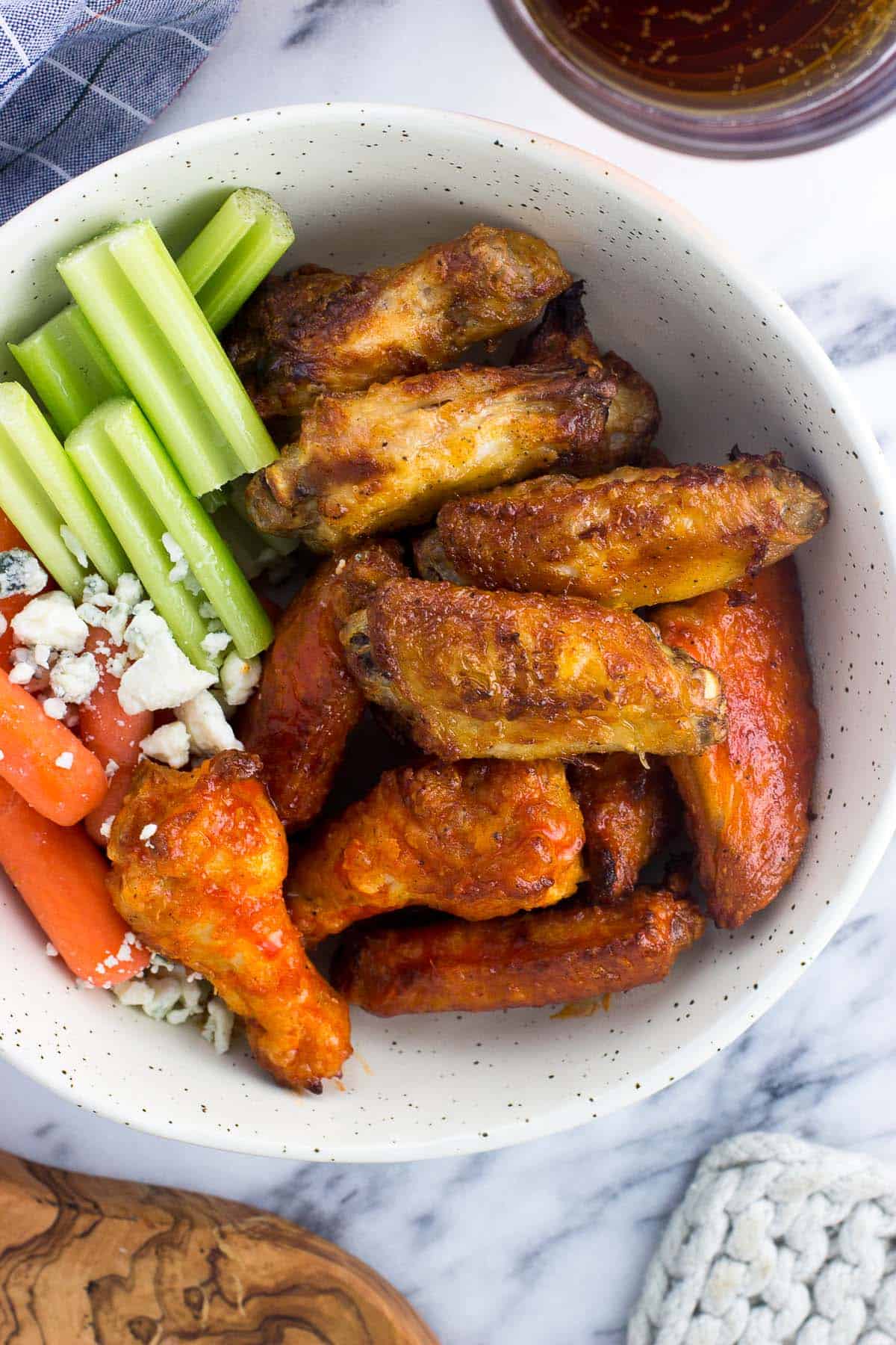 A bowl of wings, celery sticks, baby carrots, and blue cheese.